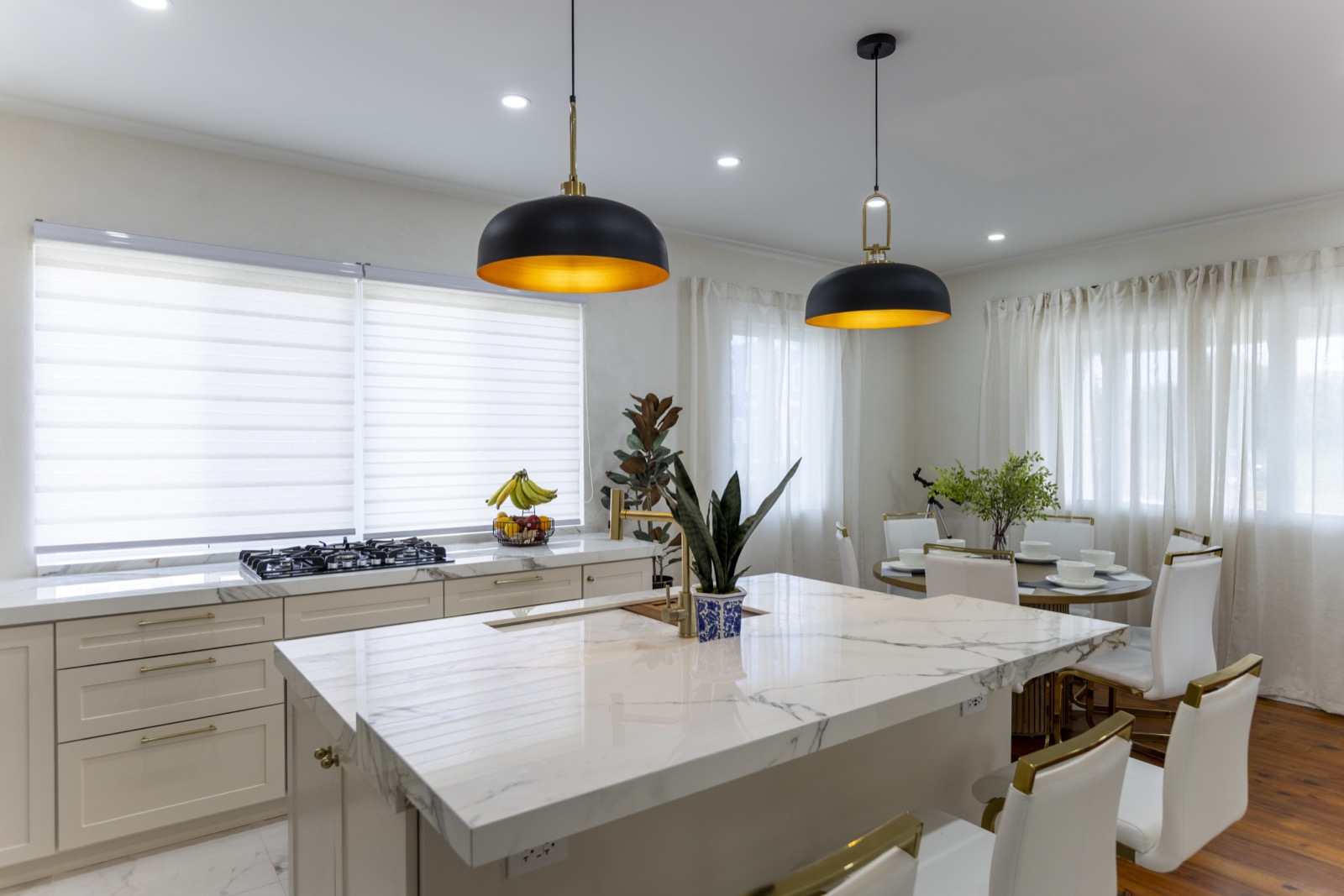 Main House kitchen — marble waterfall island and black-and-gold dome pendants
