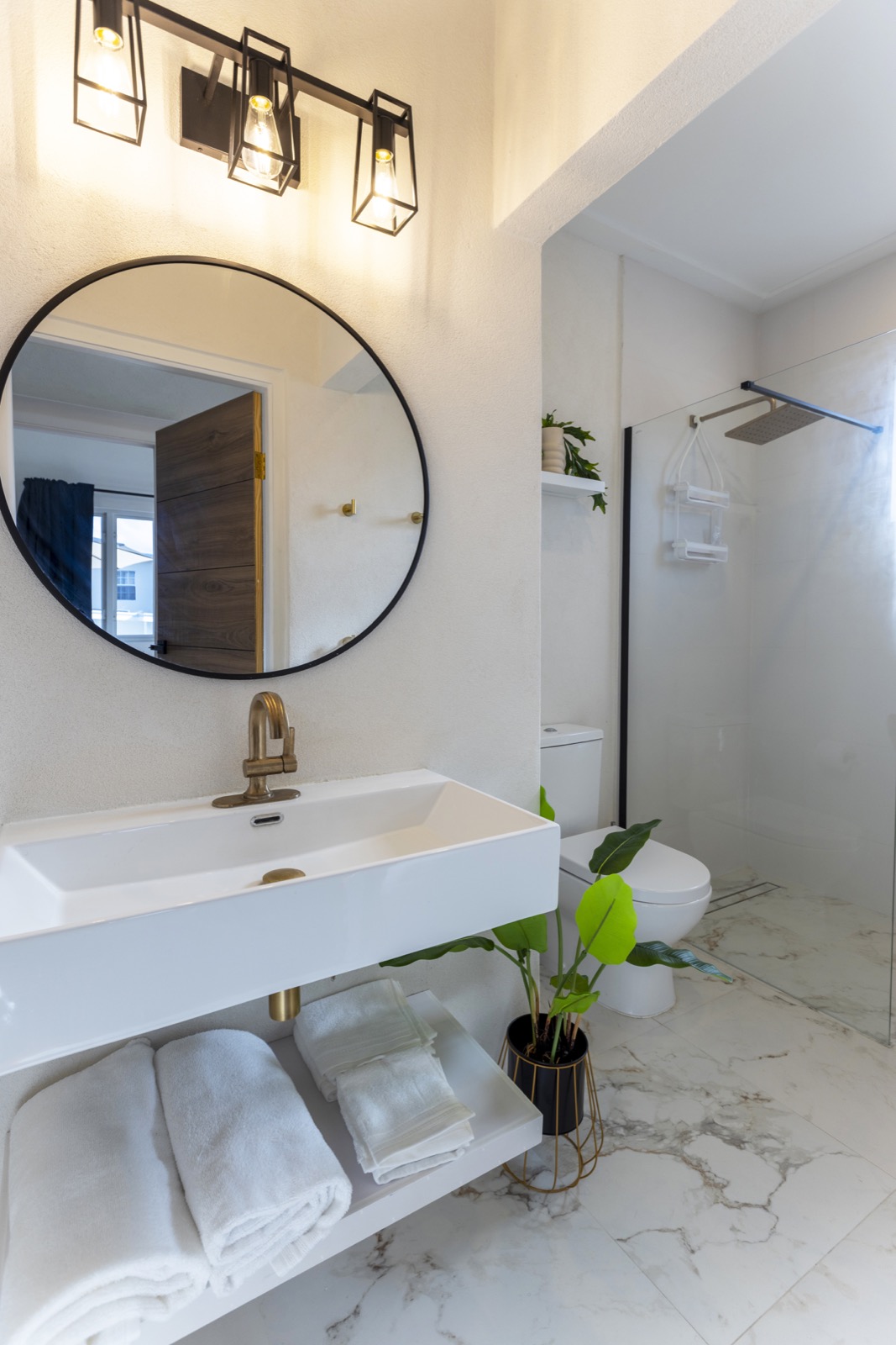 Shared bathroom — marble, brass, Edison cage vanity lights