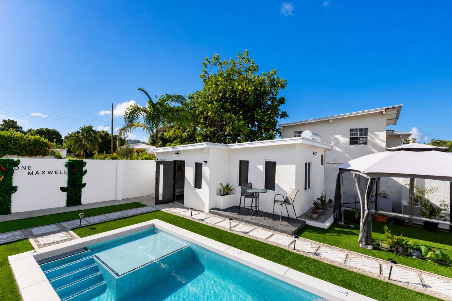 The Cottage from the pool with the ONE MAXWELL wordmark wall