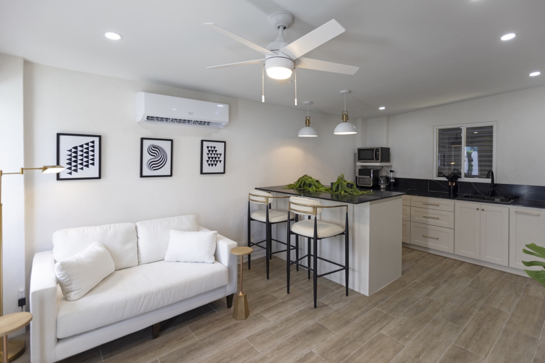 Cottage living area — white sofa, gallery wall, open-plan kitchen
