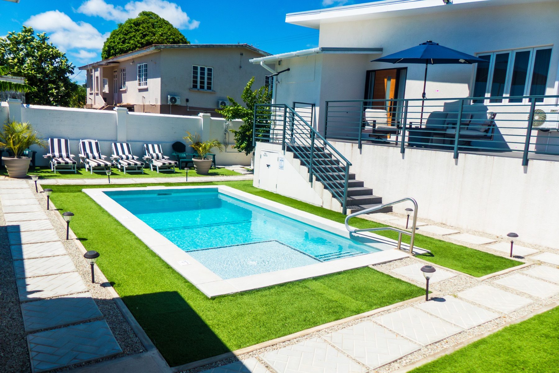 Main House from the pool — raised deck, umbrella, full elevation