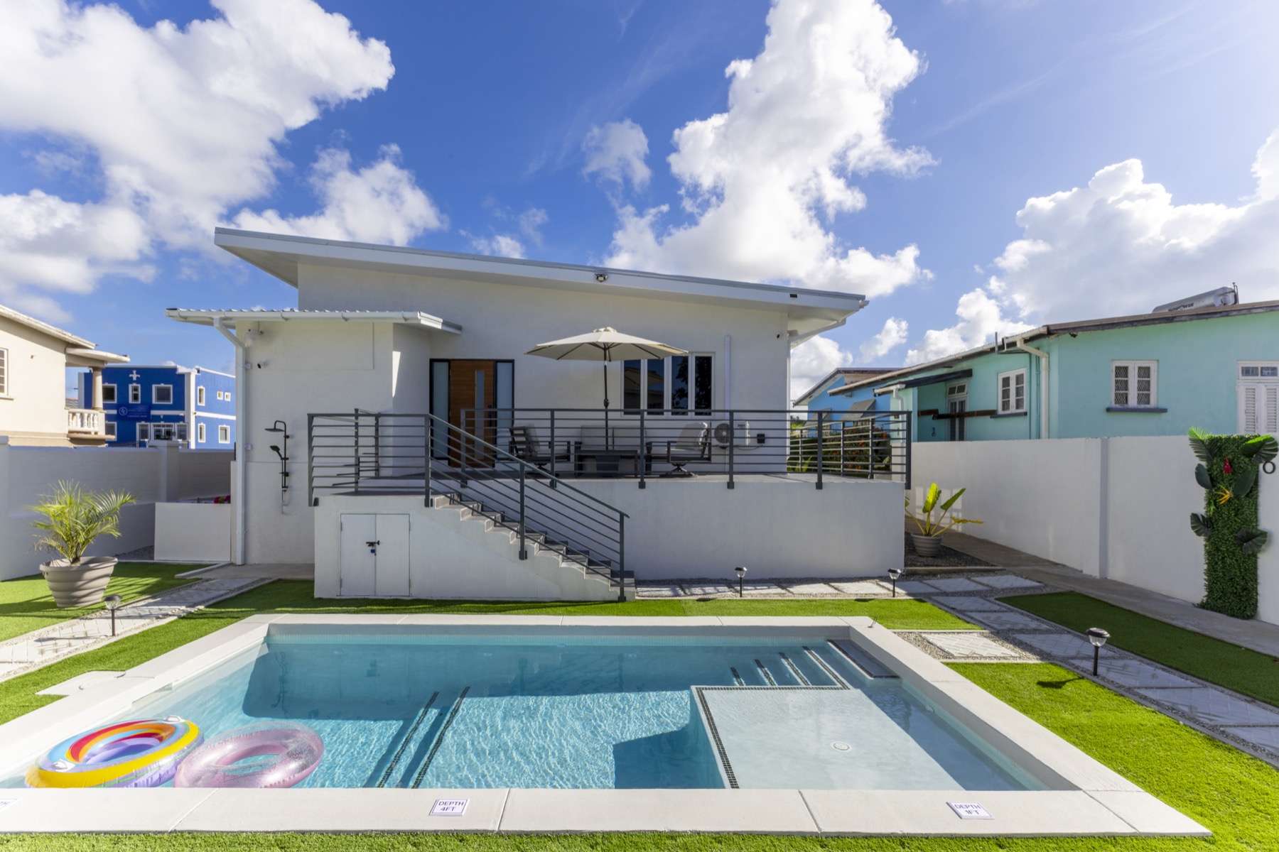 The Main House from the pool — raised deck, umbrella, full elevation