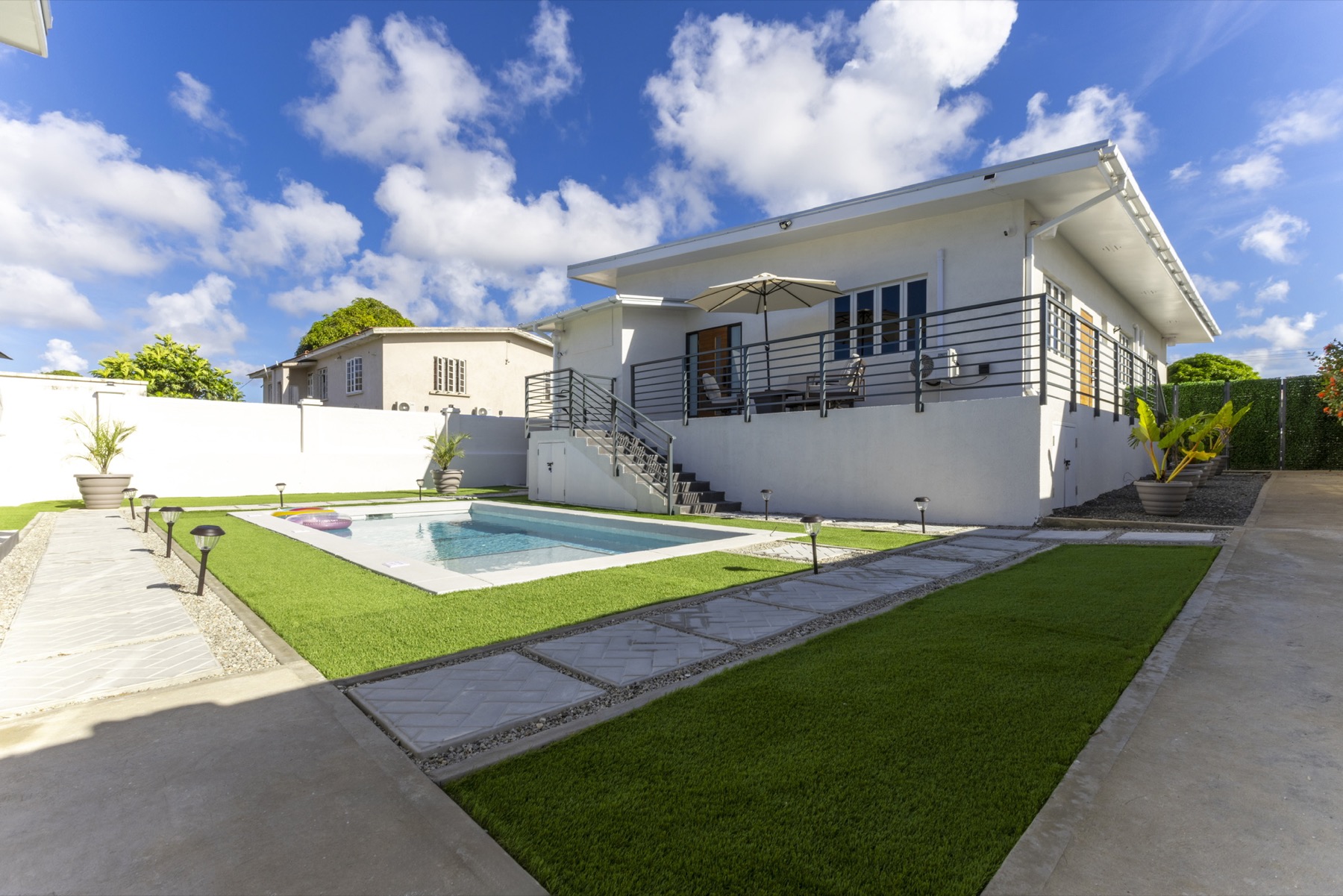 Main House from the pool — raised deck, umbrella, full elevation